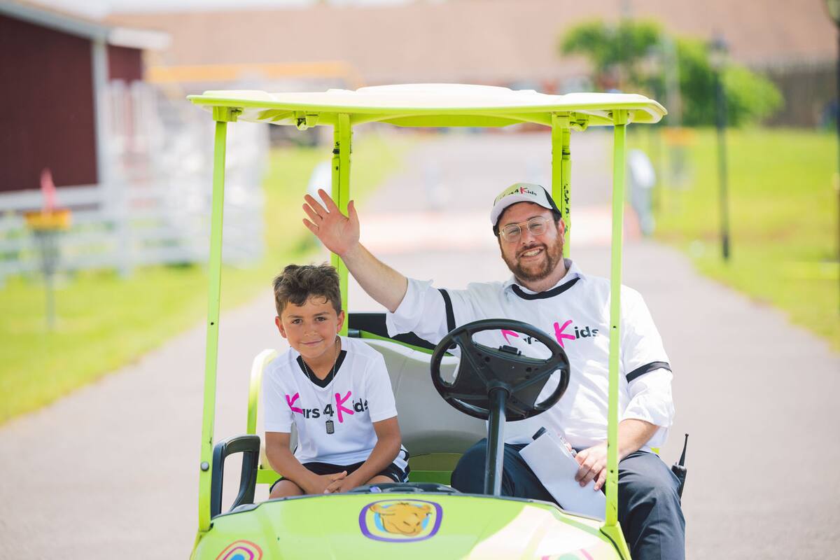 Kars4Kids volunteer and child waving from a golf cart