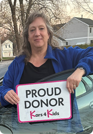 A person holding a sign that says Proud Donor Kars4Kids
