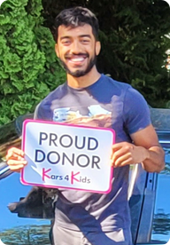 A person holding a sign that says Proud Donor Kars4Kids