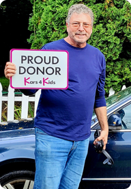 A person holding a sign that says Proud Donor Kars4Kids